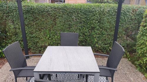 a table and two chairs with a table and a hedge at Ferienwohnung im Gutshof Direkt gegenüber dem Schloss, Rhododendronpark mit Terrasse und WLAN in Kromlau