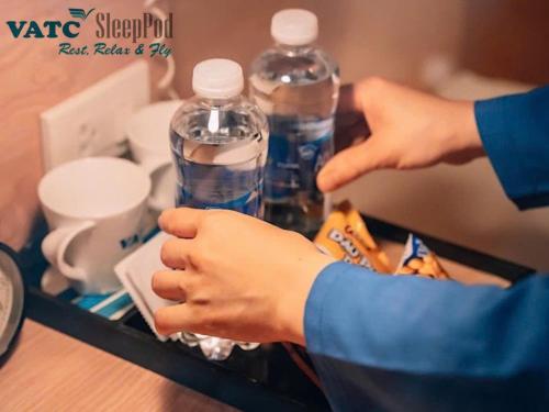 a person holding two bottles of water in a tray at VATC Sleep Pod Terminal 1 in Noi Bai