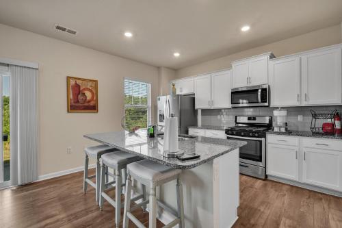 a kitchen with white cabinets and a island with bar stools at Beautifull house near Airport in Charlotte