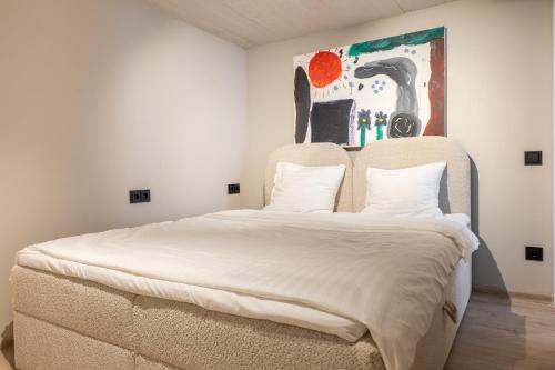ein Bett in einem Zimmer mit einem Gemälde an der Wand in der Unterkunft Mill Loft in Palanga