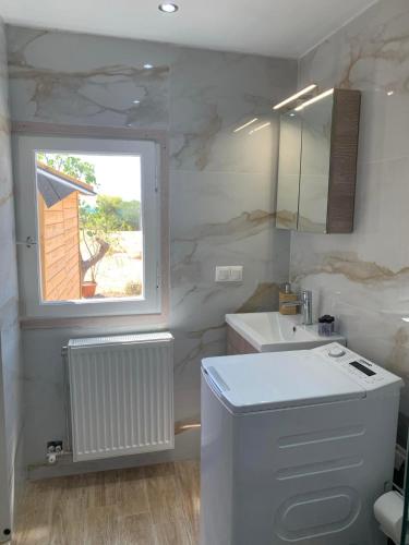 a white bathroom with a sink and a window at Aphaia Serenity Apartment in Aegina Town