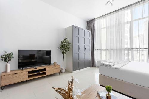 a living room with a television and a large window at Silkhaus Vacation Homes in Hydra Avenue Large Studio Near Reem Park in Abu Dhabi