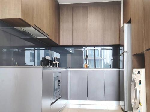 a kitchen with stainless steel appliances and wooden cabinets at GM B-1205 TWO BEDROOMS Cozy Netflix BySTAY in Iskandar Puteri