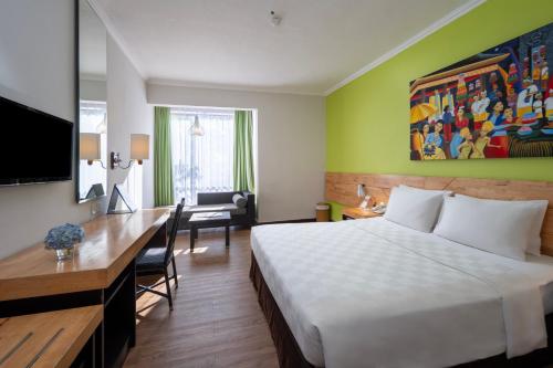 a hotel room with a white bed and a desk at Prime Plaza Hotel Sanur – Bali in Sanur