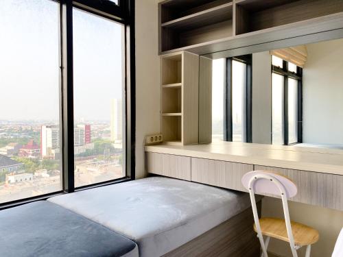 a bedroom with a bed and a window with a chair at Cozy and Comfort 2BR at Pollux Chadstone Apartment By Travelio in Cikarang