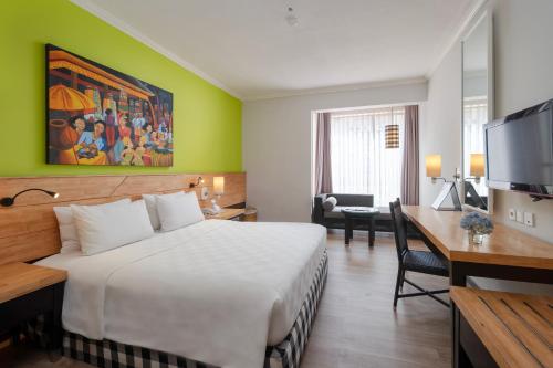 a hotel room with a large bed and a desk at Prime Plaza Hotel Sanur – Bali in Sanur