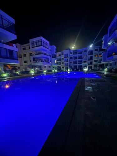 a swimming pool with blue lights in a city at night at Luxueux Appartement ensoleillé vue sur mer in Pont Blondin