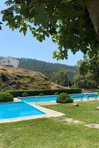 a swimming pool with two benches in the grass at Casas do Gato in Valezim