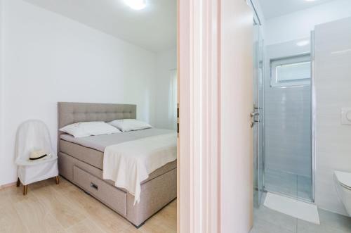 ein weißes Schlafzimmer mit einem Bett und einer Dusche in der Unterkunft Leng in Dramalj
