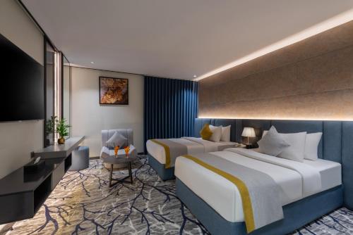 a hotel room with two beds and a chair at Ross Hotel in Riyadh
