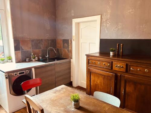 a kitchen with a table and a sink and a stove at LA MARIEFACTURE - Comme chez le Baron in Saint-Avold