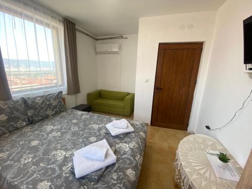 a hotel room with a bed and a green chair at Анелия in Sapareva Banya