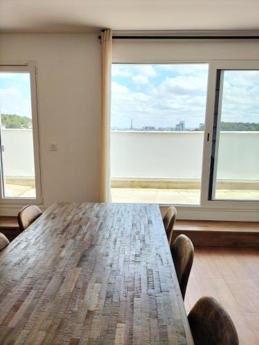 a table in a room with a view of the water at Penthouse vue Tour Eiffel, près Château Versailles in Sèvres