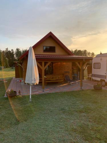 a wooden cabin with an umbrella in the grass at Domek Letniskowy z prywatną plażą in Czarnakowizna