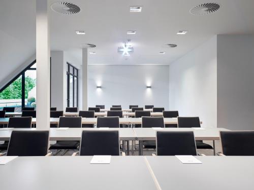 an empty lecture room with tables and chairs at Hotel Gut Kaden in Alveslohe