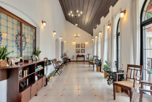 einen Flur mit Stühlen und Tischen in einem Gebäude in der Unterkunft SaffronStays Biccode Woodside Heritage in Belūr
