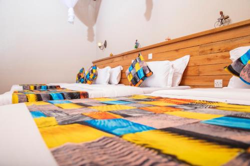 two beds in a room with a colorful blanket at Kaswa Lodge in Fort Portal