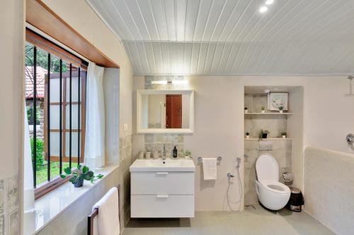 une salle de bain avec un lavabo et des toilettes et une fenêtre dans l'établissement SaffronStays Biccode Woodside Heritage, à Belūr