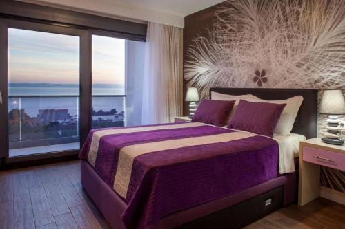 a bedroom with a purple bed and a large window at Villa Ribica in Veliko Brdo