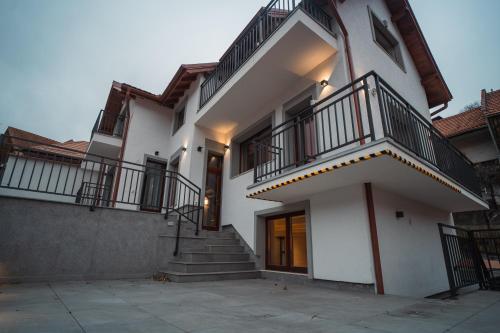 a white house with stairs and a balcony at Zen Den in Braşov