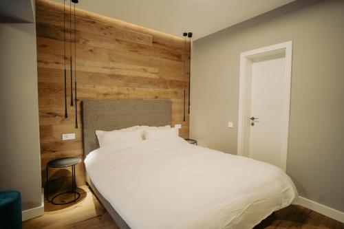 a bedroom with a white bed and a wooden wall at Zen Den in Braşov