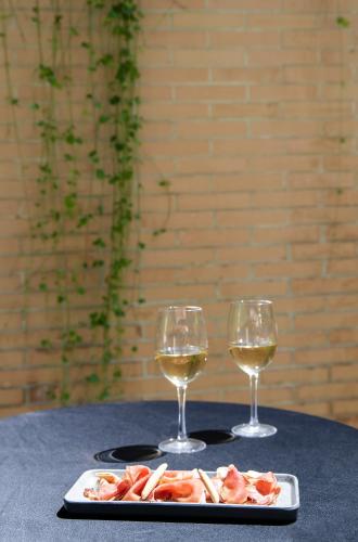 two glasses of wine and a plate of food on a table at Hotel Granada by Pierre & Vacances in Granada