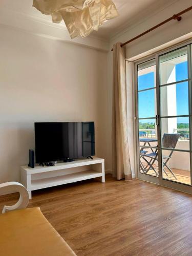 a living room with a tv and a large window at Lagoa Beach & Leisure in Costa de Santo André