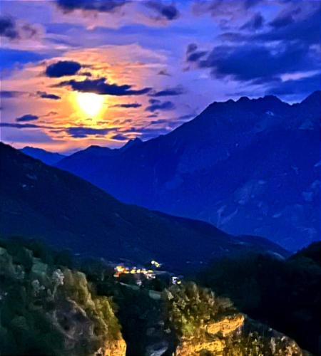 a sunset over a mountain range with the sun in the sky at CHALET con JACUZZI VISTA MONTAGNE in Aosta