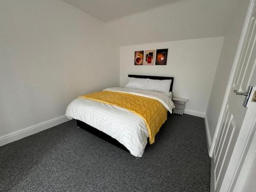a small bedroom with a bed with a yellow blanket at Work & Relax- Convenient 2-Bed House in Grimsby