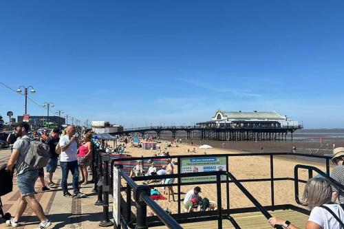 a group of people walking on the beach near a pier at Work & Relax- Convenient 2-Bed House in Grimsby
