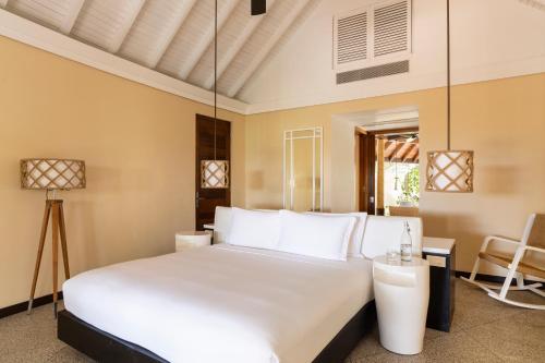 a bedroom with a white bed and a table at Constance Halaveli in Hangnaameedhoo