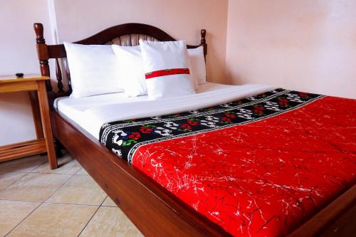 a bed with a red blanket on top of it at Westend Motel in Fort Portal