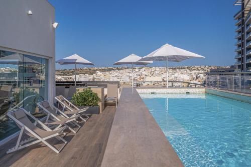 a swimming pool with chairs and umbrellas on a building at Hotel Mistral St Julian's, Affiliated by Meliá in St Julian's