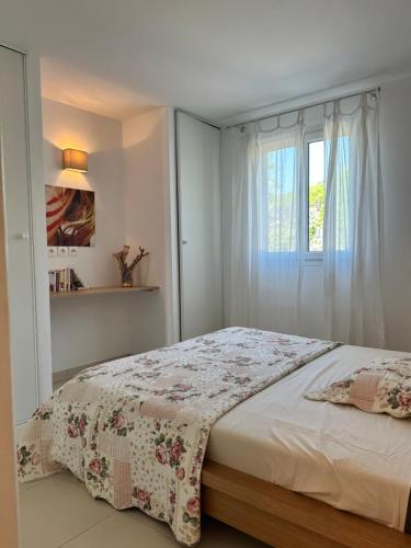 - une chambre avec un lit doté d'un couvre-lit floral et d'une fenêtre dans l'établissement Évasion en Méditerranée, à La Garonnette-Plage