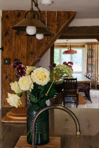 a vase of flowers sitting on a kitchen sink at Gorgeous English Farmhouse Holiday Cottage for 9 and a half in Ellingham