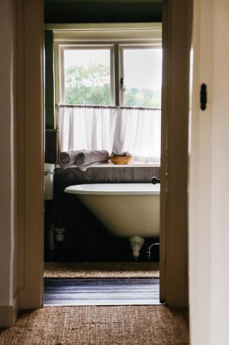 a bathroom with a bath tub and a window at Gorgeous English Farmhouse Holiday Cottage for 9 and a half in Ellingham