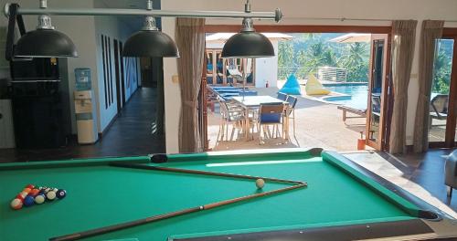 a pool table in a living room next to a swimming pool at Villa E in Taling Ngam Beach