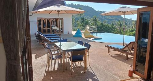 a patio with tables and chairs and a swimming pool at Villa E in Taling Ngam Beach
