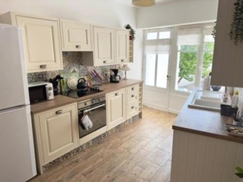 a kitchen with white cabinets and a stove top oven at Charming Countryside House in Beauvais with pool in Beauvais-sur-Matha
