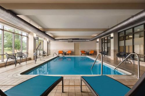 a pool in a hotel with tables and chairs at Hampton Inn & Suites Pittsburgh Waterfront West Homestead in West Homestead