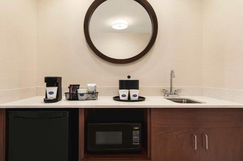 a kitchen with a sink and a microwave and a mirror at Hampton Inn & Suites Pittsburgh Waterfront West Homestead in West Homestead