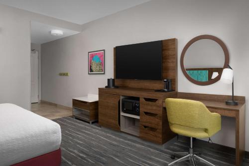 a hotel room with a bed and a desk with a television at Hampton Inn & Suites Durham North I-85 in Durham