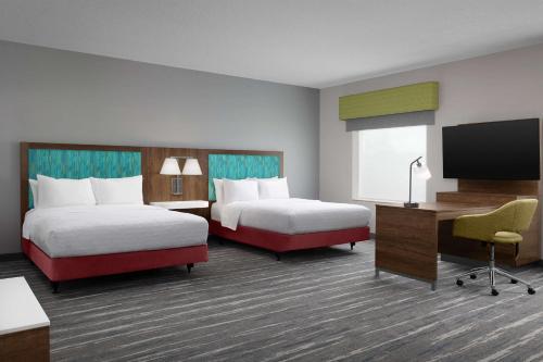 a hotel room with two beds and a flat screen tv at Hampton Inn & Suites Durham North I-85 in Durham