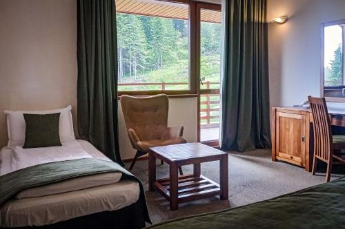 ボロヴェッツにあるMusala Hotelのベッド、椅子、デスクが備わる客室です。