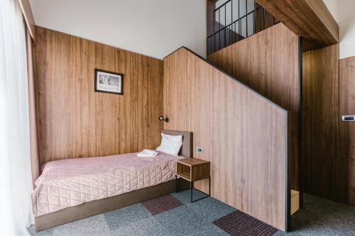 a small bedroom with a bed and a staircase at Rtanj Kopaonik Eco Resort & Spa in Kopaonik