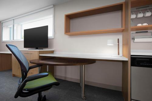 an office with a desk and a chair and a television at Home2 Suites by Hilton Eugene Downtown University Area in Eugene
