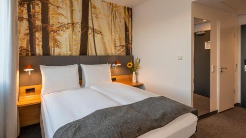 a bedroom with a large white bed with a painting on the wall at Holiday Inn Munich - Leuchtenbergring by IHG in Munich