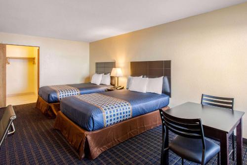 a hotel room with two beds and a table and chair at Rodeway Inn Coeur d'Alene in Coeur d'Alene