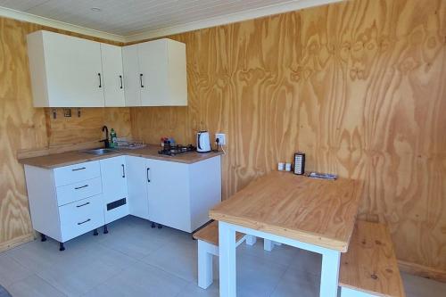 a kitchen with white cabinets and a wooden table at Quaint Cottage With Harbour Views in Cape Town