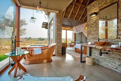 a large room with a tub and a bedroom at Elephant Point in Skukuza